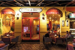 A cozy cafe with a checkered floor and red-brick walls, featuring tables and chairs for patrons. - Paralia Khem Beach Phu Quoc Hotel (Phu Quoc)