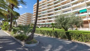 Un hotel de varios pisos con balcones, rodeado de palmeras y vegetación.