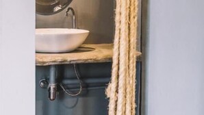 A bathroom with a round mirror, a sink, and a rope hanging from the ceiling. - Time Sabai 134 - Hostel (Bangkok)