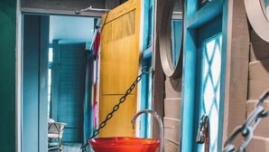A bathroom with two red sinks, a wooden vanity, and a blue door with a window. - Time Sabai 134 - Hostel (Bangkok)