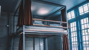 A bunk bed room with a window, curtains, and a wall-mounted air conditioning unit. - Time Sabai 134 - Hostel (Bangkok)
