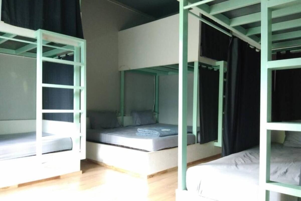 A room with bunk beds, a mattress on the floor, and a window with curtains.