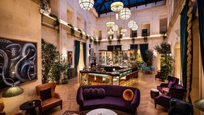 A spacious lobby with a high ceiling, multiple seating areas, a bar, and a large artwork on the left. - The Merchant Baku (Baku)