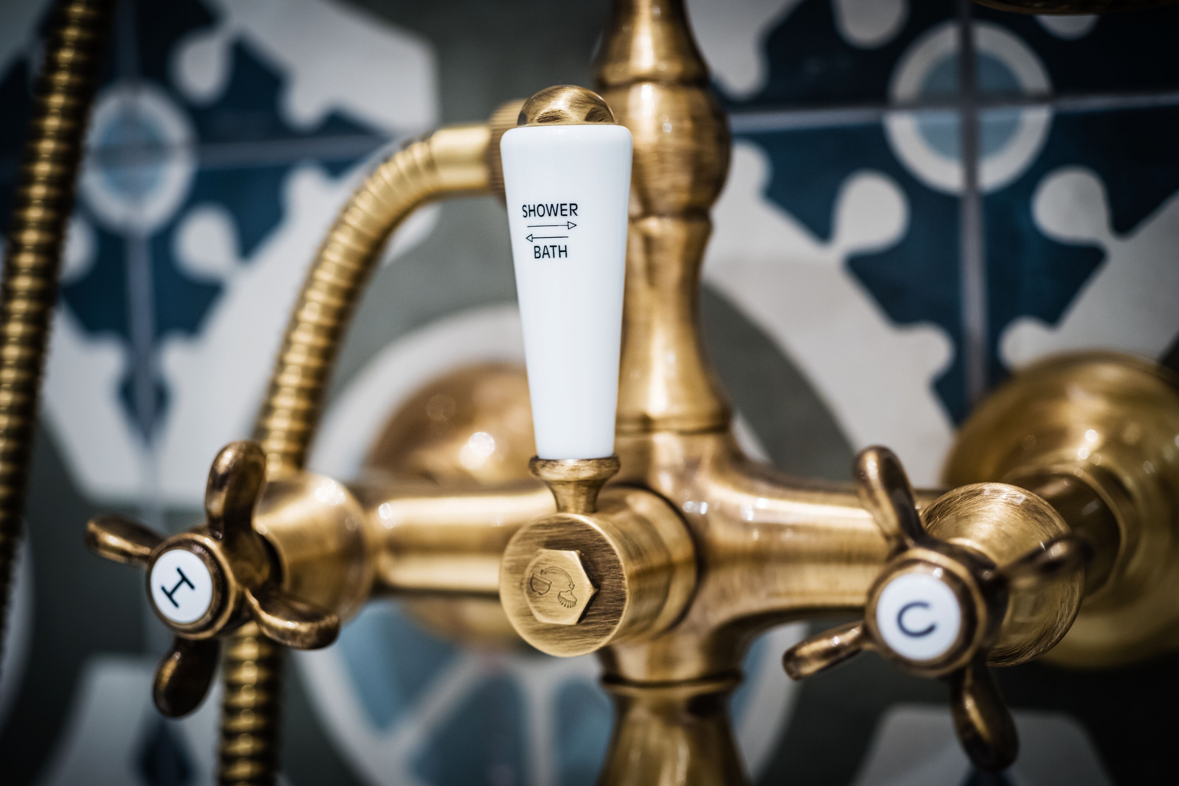 Un robinet de salle de bain en laiton, doté d’une poignée blanche portant l’inscription « DOUCHE/BAIN » et de trois boutons de commande marqués des lettres « H », « C » et « L ».
