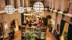 A spacious lobby with a high ceiling, wooden flooring, and a central seating area with tables and chairs. - The Merchant Baku (Baku)