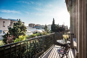 A balcony with a table and chairs, potted plants, and a view of surrounding buildings.