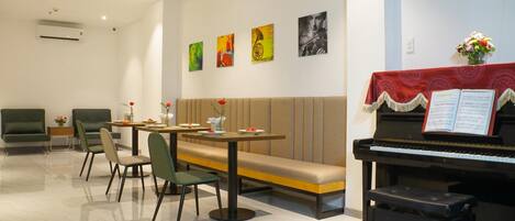 A dining area with a piano, a bench, and a table set for two.