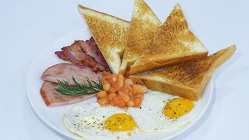 A plate of breakfast food including toast, bacon, eggs, and beans.