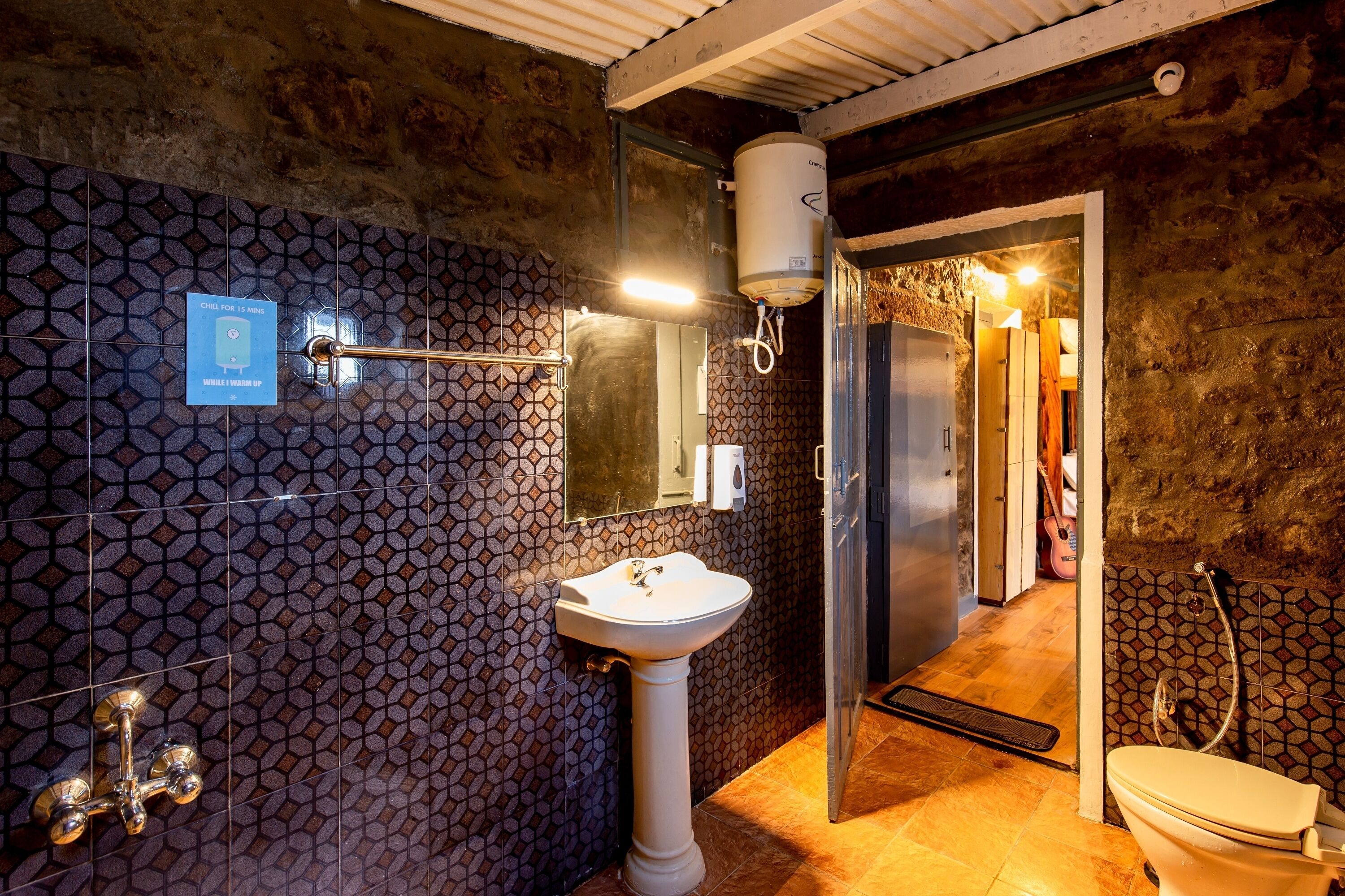 Ein Badezimmer mit gefliesten Wänden, einem Waschbecken auf Säule, einer Toilette und einer Duschkabine.