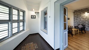 Un pasillo con alfombra estampada, suelo de madera, pared de piedra y una silla.