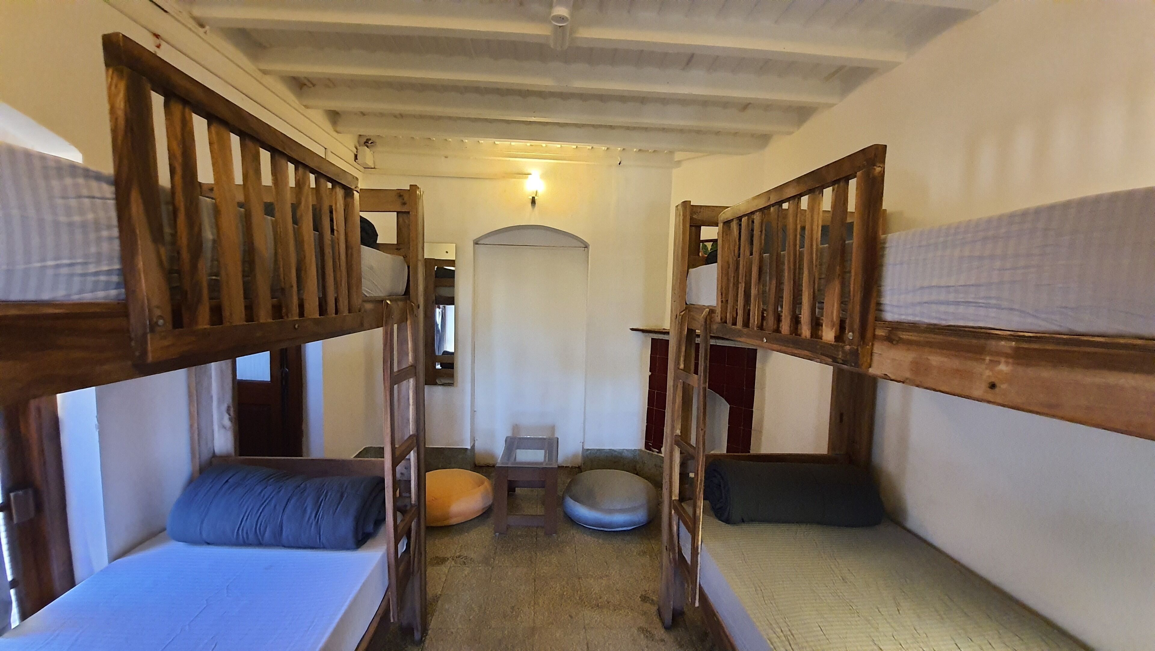 A narrow corridor with bunk beds on either side, a small stool, and a round pet bed in the center.