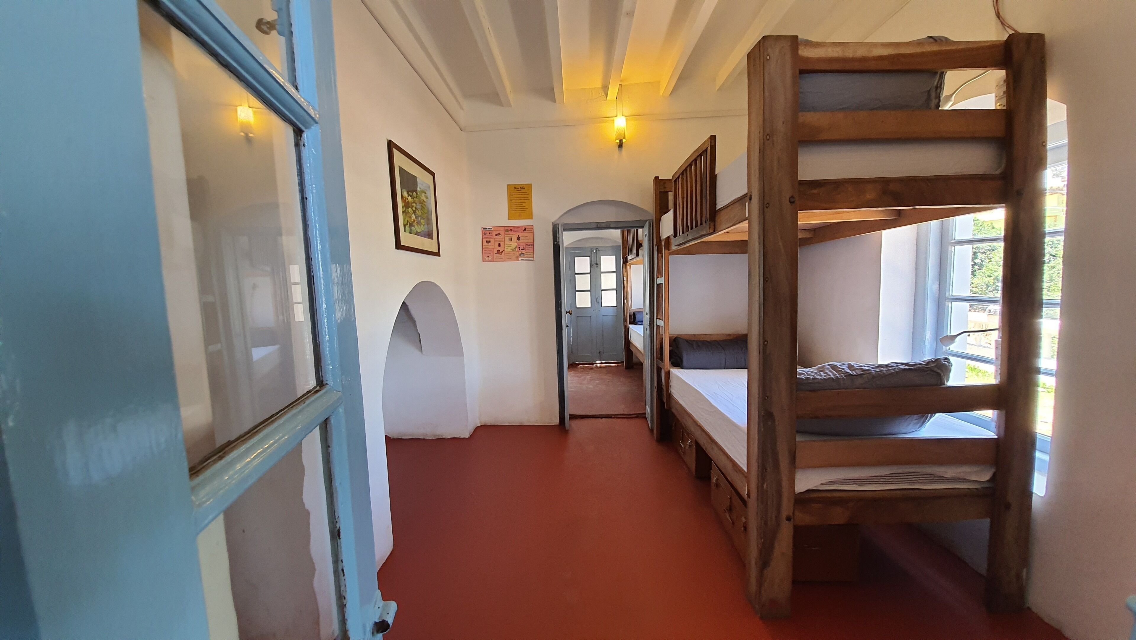 A narrow hallway with bunk beds, a door with a blue frame, and a small archway.