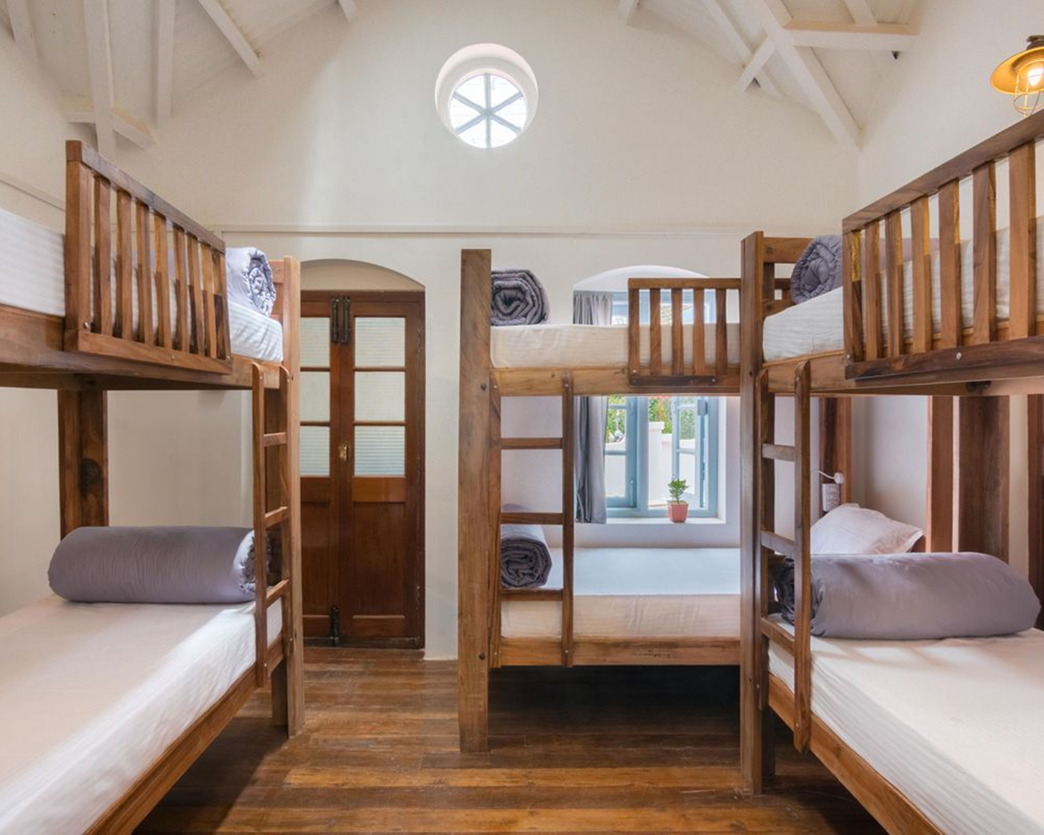 A room with three bunk beds, wooden flooring, a skylight, and a door with frosted glass panels.
