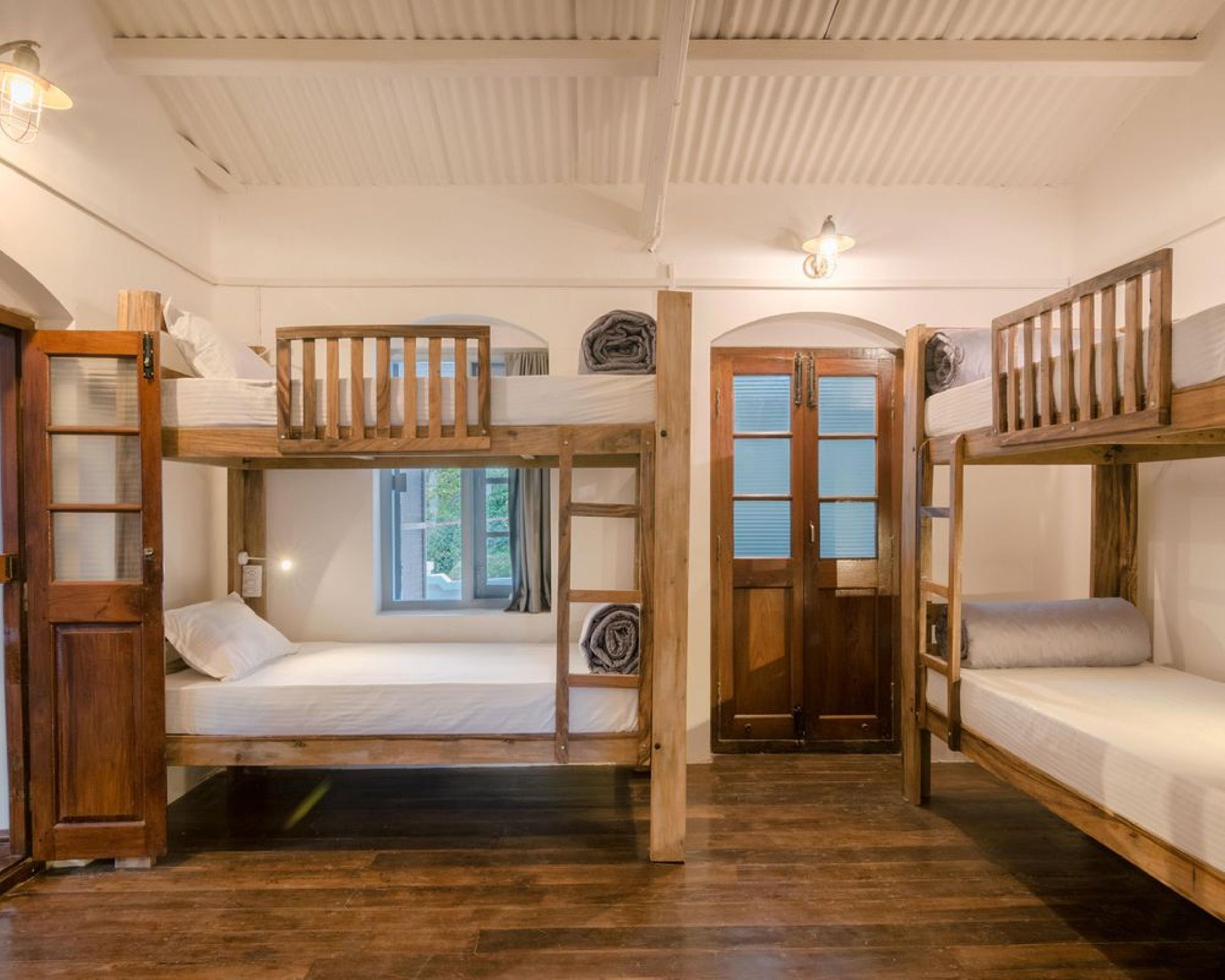 A room with bunk beds, wooden doors, and a window.