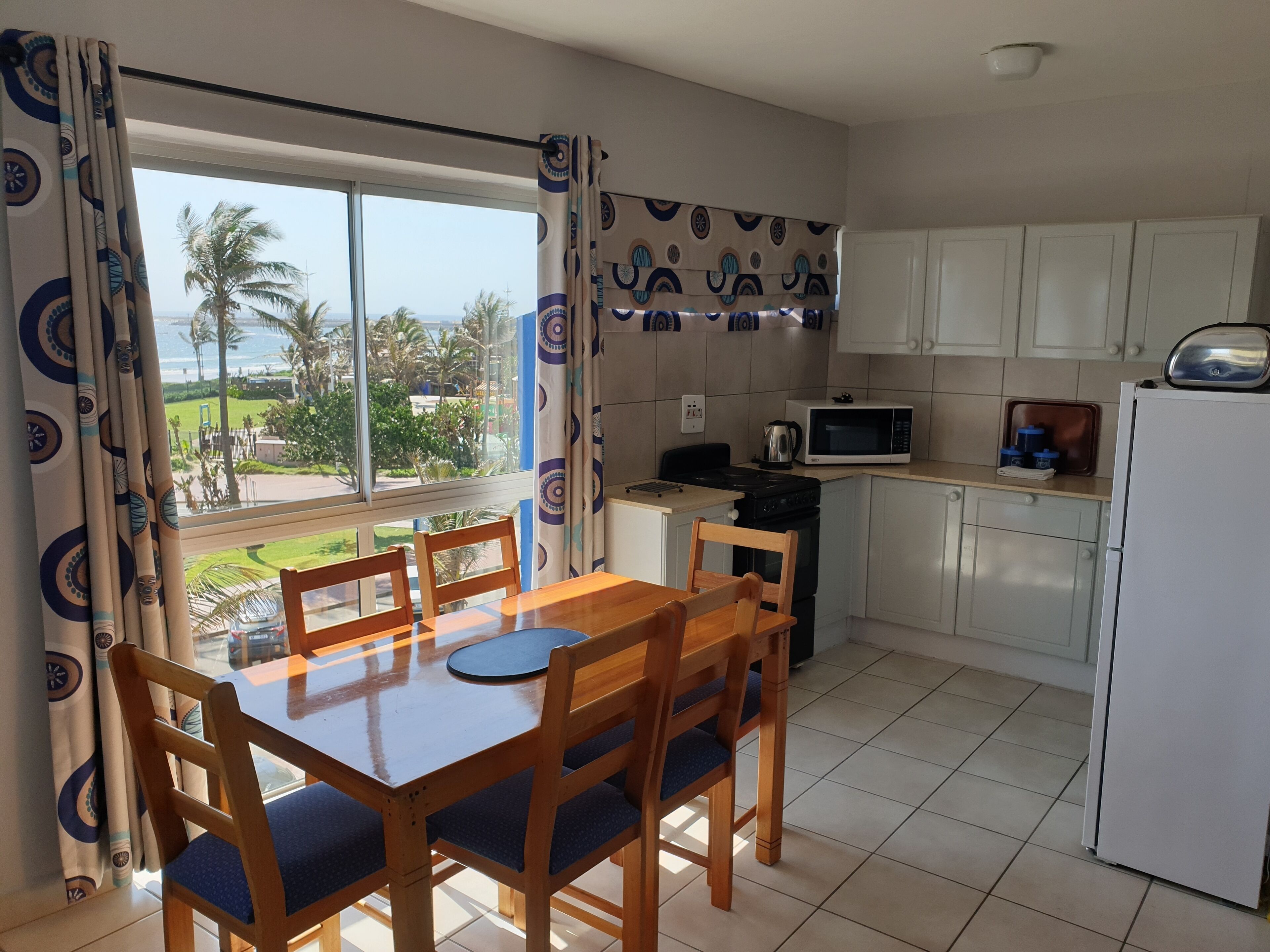 A kitchen with a dining table and chairs, a microwave, and a refrigerator.