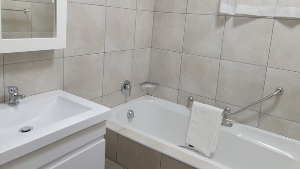 Un baño con lavamanos blanco, bañera y espejo.