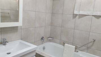 Ein Badezimmer mit einem weißen Waschbecken, einer Badewanne und einem Spiegel.