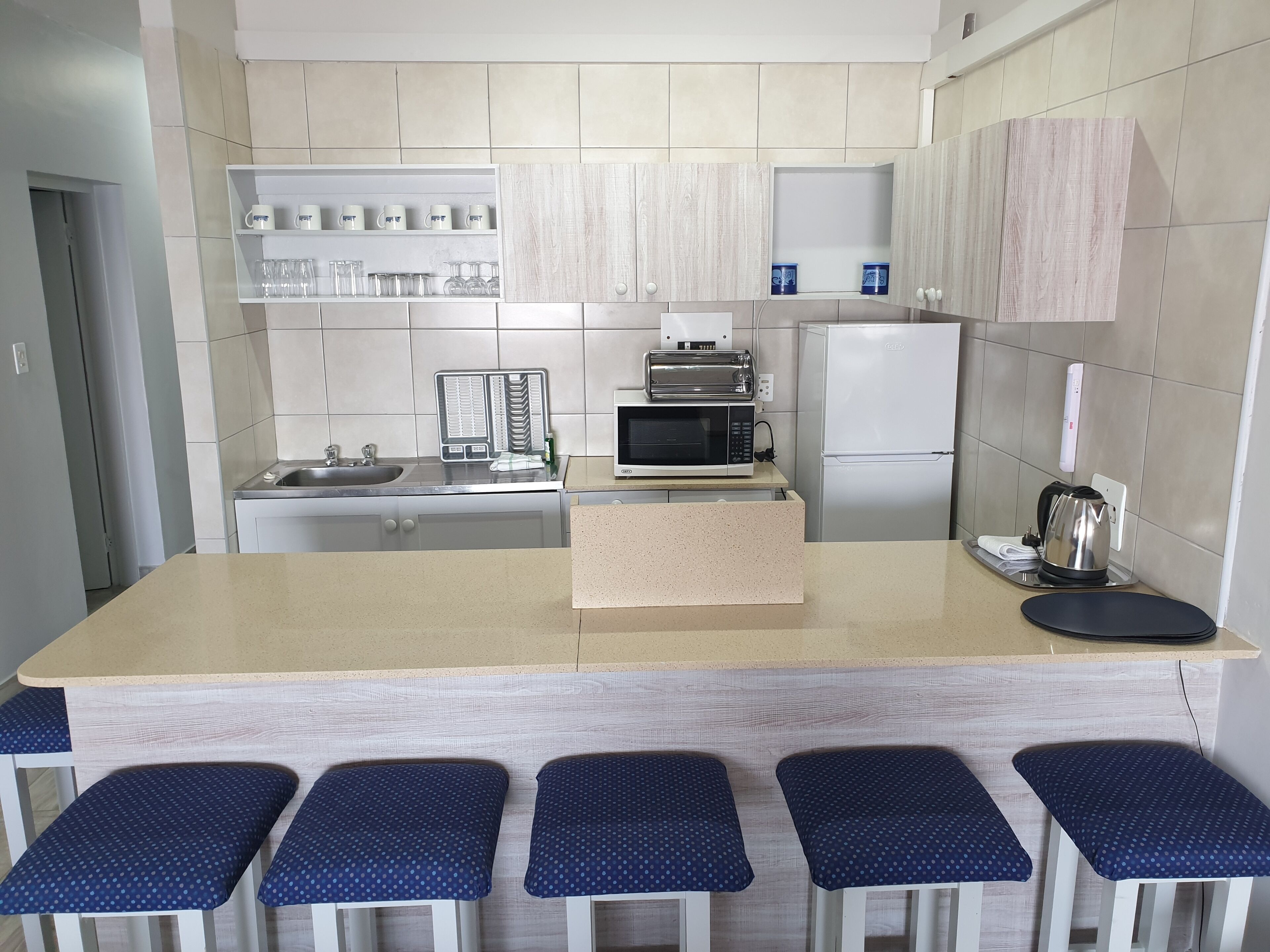 Una cocina moderna con una isla central, taburetes de bar y un microondas.