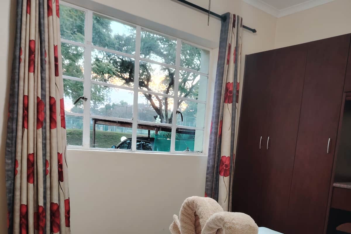 Een hotelkamer met een bed, een raam met gordijnen en een kledingkast.
