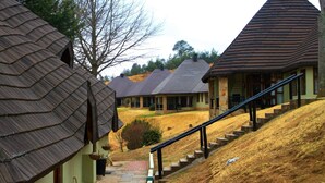 Un paysage rural avec des maisons traditionnelles aux toits de chaume et un bâtiment moderne doté d’un toit en pente.