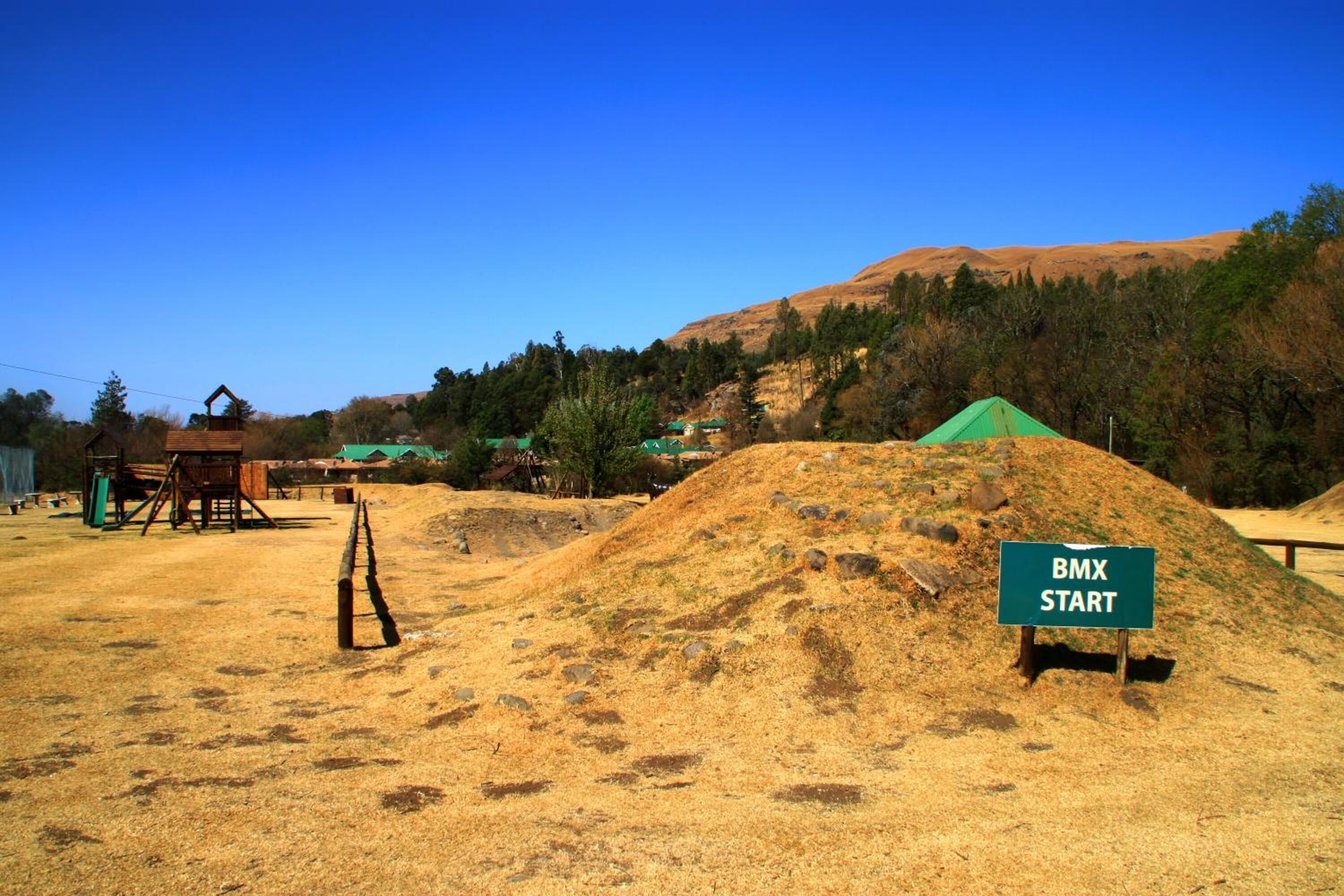 A BMX start area with a dirt mound and a wooden structure.