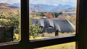Une vue à travers la fenêtre d’une maison avec un toit en pente, sur laquelle on peut voir le numéro « 123 » et un panneau circulaire rouge.