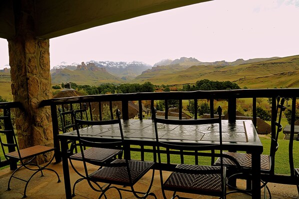 A patio with a table and chairs overlooking a mountainous landscape.