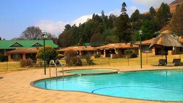Una piscina al aire libre, sillones reclinables de piscina