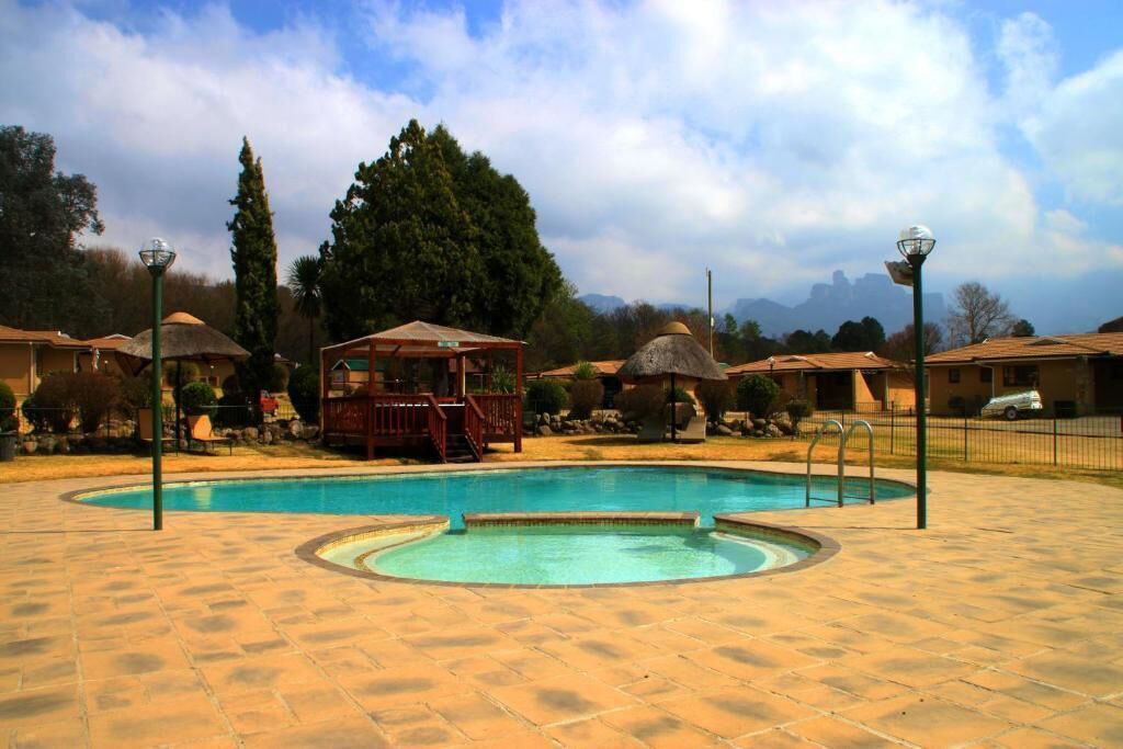 Una piscina con un hidromasaje circular, rodeada de sillas de descanso y un pabellón.