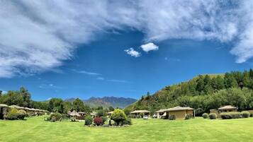 A resort with multiple bungalow-style buildings, a well-maintained lawn, and a mountainous backdrop.