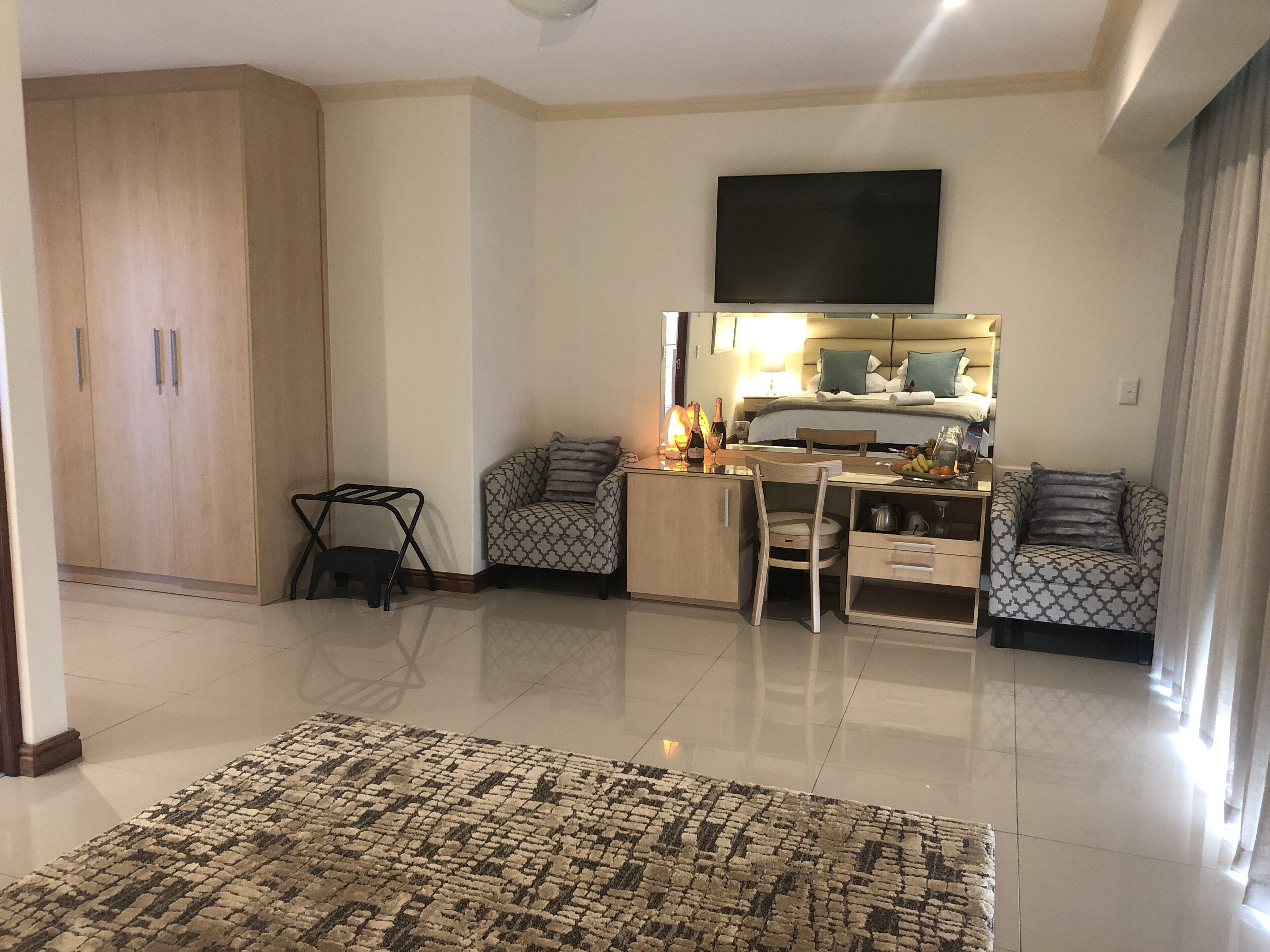A modern living room with a flat-screen TV, a dining area with a table and chairs, a sofa, and a patterned rug.