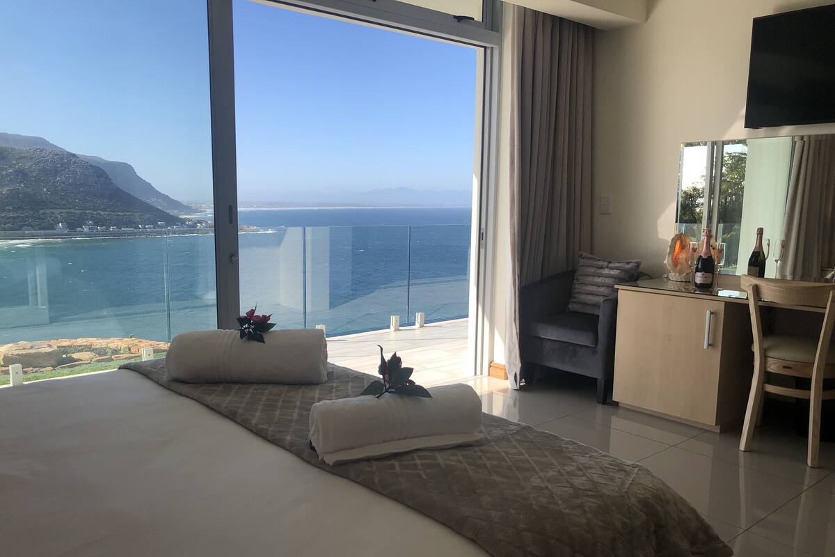 A hotel room with a large bed, a desk, and a view of the ocean.