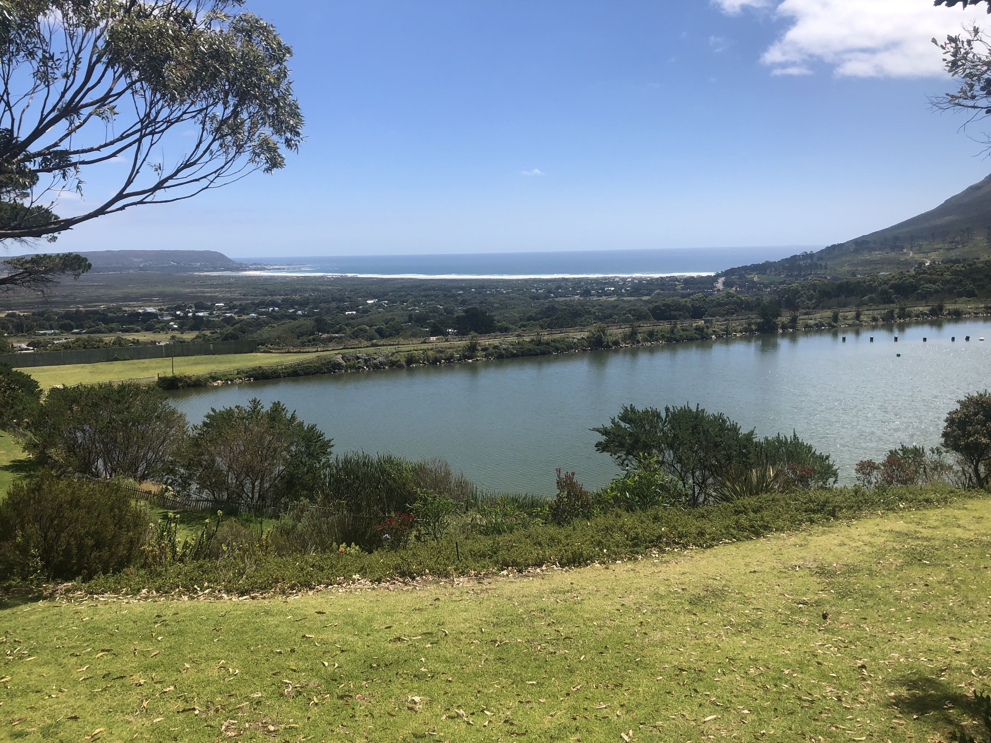 Ein See, umgeben von grüner Landschaft und Hügeln.