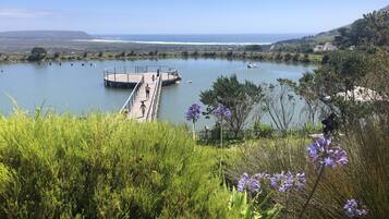 Un lago con un molo di legno che si protende sull'acqua, circondato da vegetazione e colline sullo sfondo.