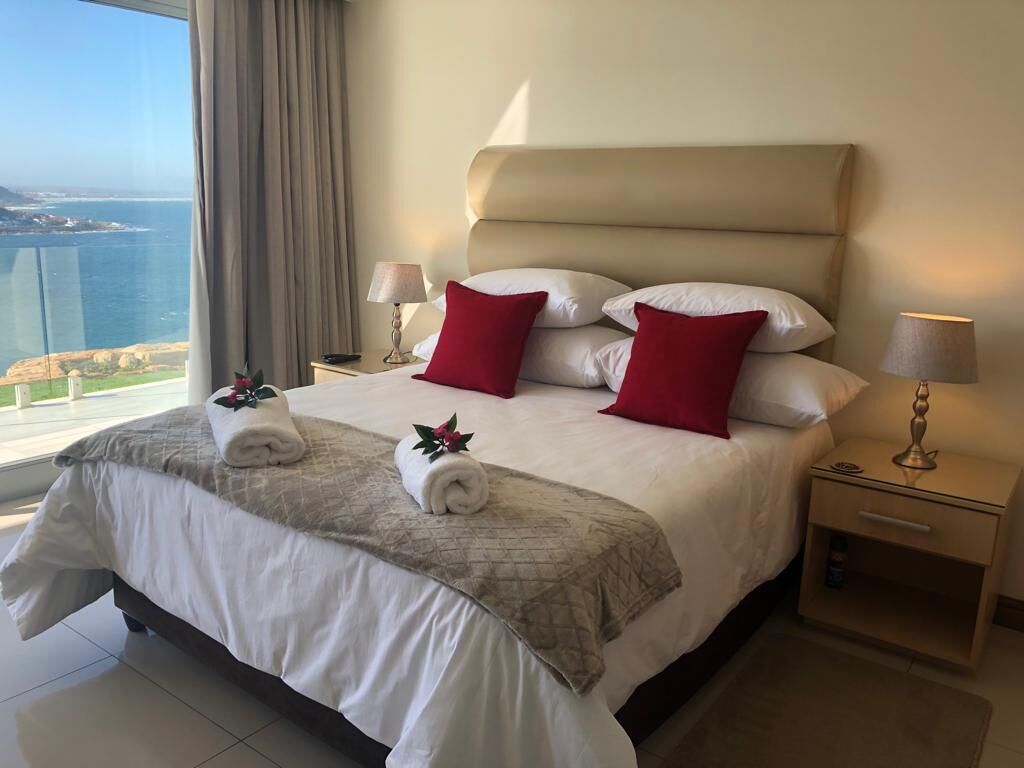 Une chambre d’hôtel avec un grand lit, deux tables de chevet et une vue sur la mer.