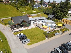An aerial view of a hotel with a large dining area, outdoor seating, and a parking lot. - Styrian apartment with large balcony - Steirer Apartment (Semmering-Kurort)