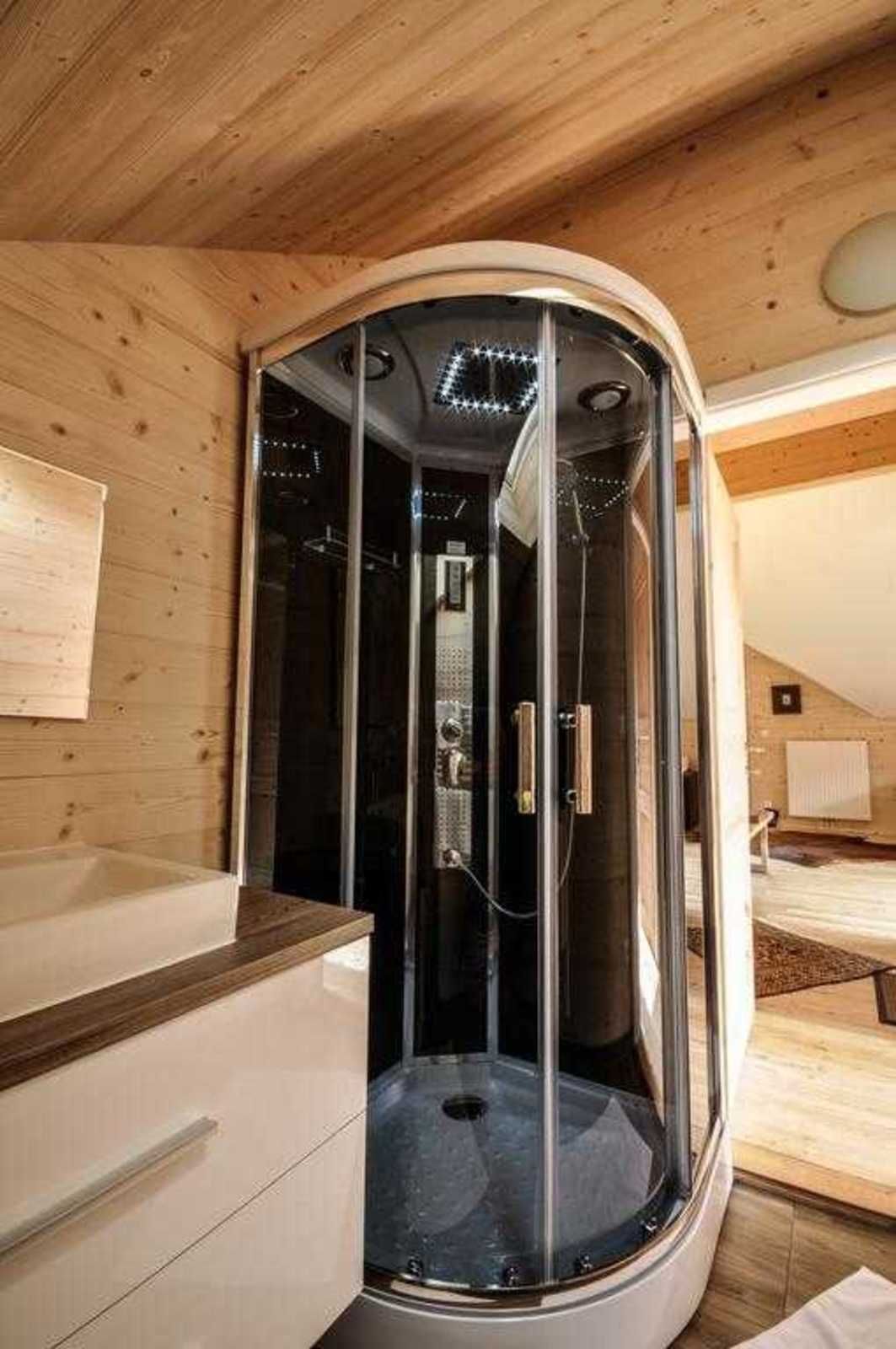 Ein modernes Badezimmer mit einer Duschkabine, Holzwänden und einem sichtbaren Handtuchhalter.