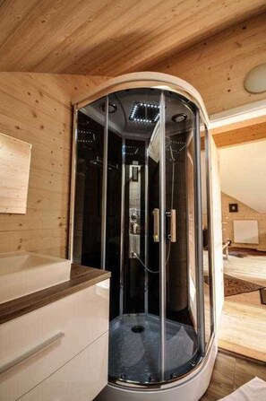 A modern bathroom with a glass-enclosed shower, wooden walls, and a visible towel rack. - Styrian apartment with large balcony - Steirer Apartment (Semmering-Kurort)