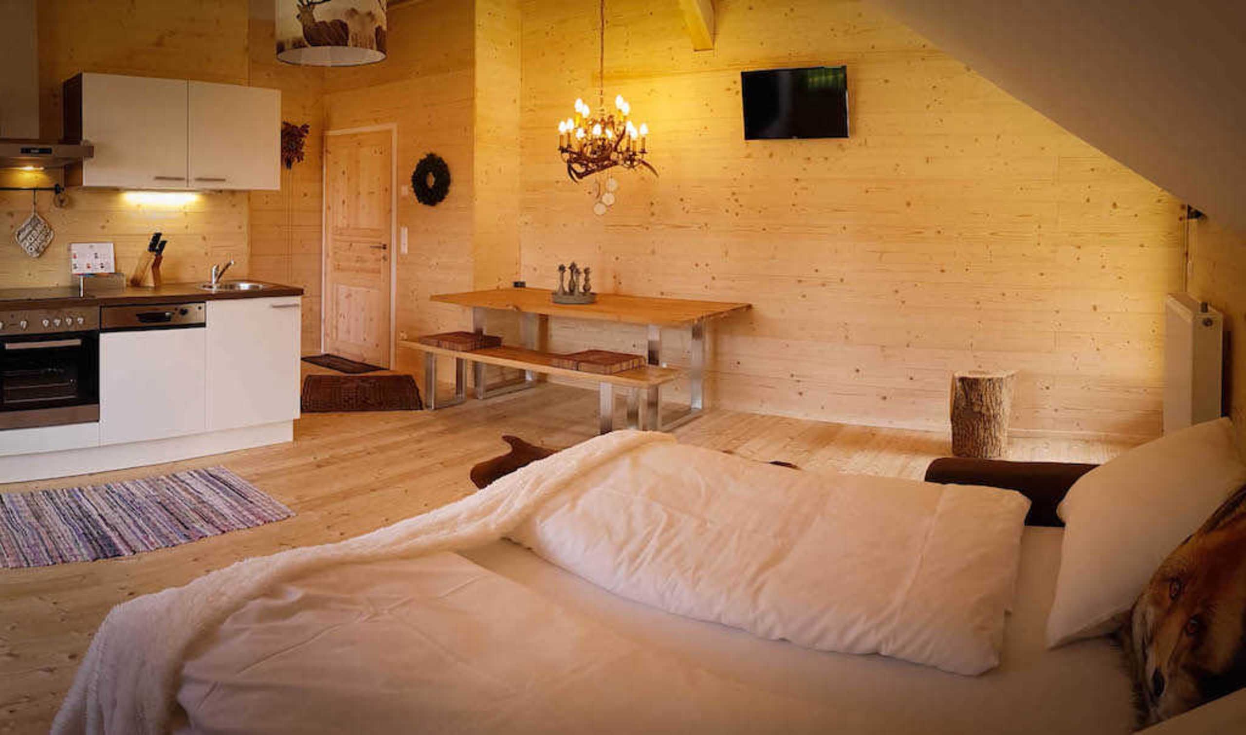 Ein gemütliches Zimmer mit einem Bett, einem Holztisch, einer Küchenzeile und einem Kamin.