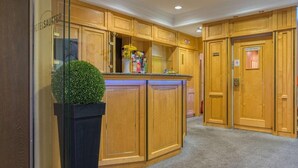 Un vestíbulo de hotel con paneles de madera, un mostrador de recepción y una planta en maceta.