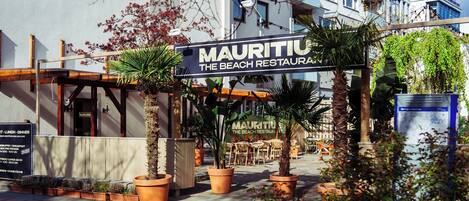 A restaurant named 'Mauritius The Beach Restaurant' with outdoor seating and potted plants.