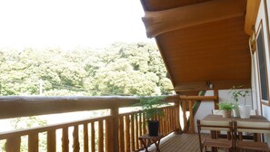 A wooden deck with a table and chairs, surrounded by potted plants. - Shimano Log House (Iki)