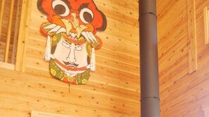 A wooden interior with a black stove, a wooden door, and a wooden wall with a picture. - Shimano Log House (Iki)
