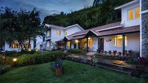 Propiedad residencial con jardín cuidado, varios accesos y fachada de piedra.