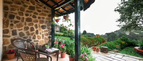 A covered patio with stone walls, a table with chairs, and potted plants.