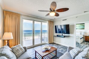 Habitación de hotel con balcón, televisión de pantalla plana, cama y ventilador de techo.