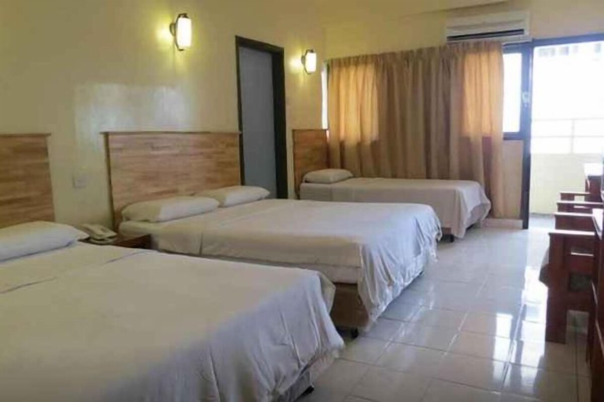 Habitación de hotel con tres camas, un escritorio y una silla.