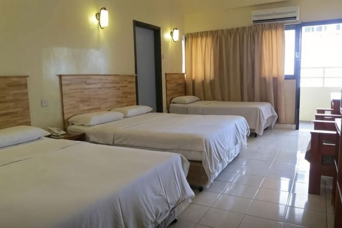 Een hotelkamer met drie bedden, een bureau en een stoel.