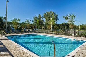 A rectangular swimming pool with clear blue water, surrounded by a tiled deck and a metal fence. - Fairfield by Marriott Inn & Suites Deerfield Beach Boca Raton (Deerfield Beach)