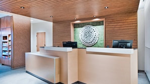 A reception area with a wooden ceiling, a large circular artwork on the wall, and a counter with two Lenovo computers. - Fairfield by Marriott Inn & Suites Deerfield Beach Boca Raton (Deerfield Beach)
